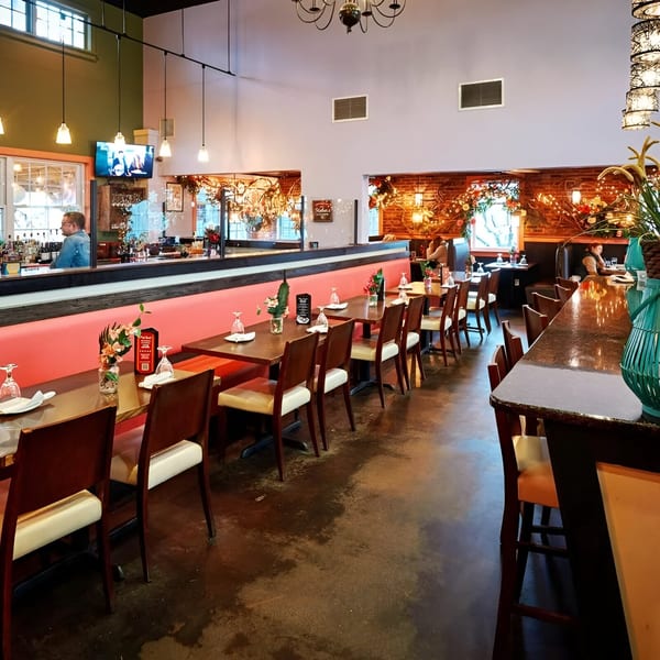 Pink Basil's Asian-fusion restaurant interior with dining tables, bar, and decorative lighting.